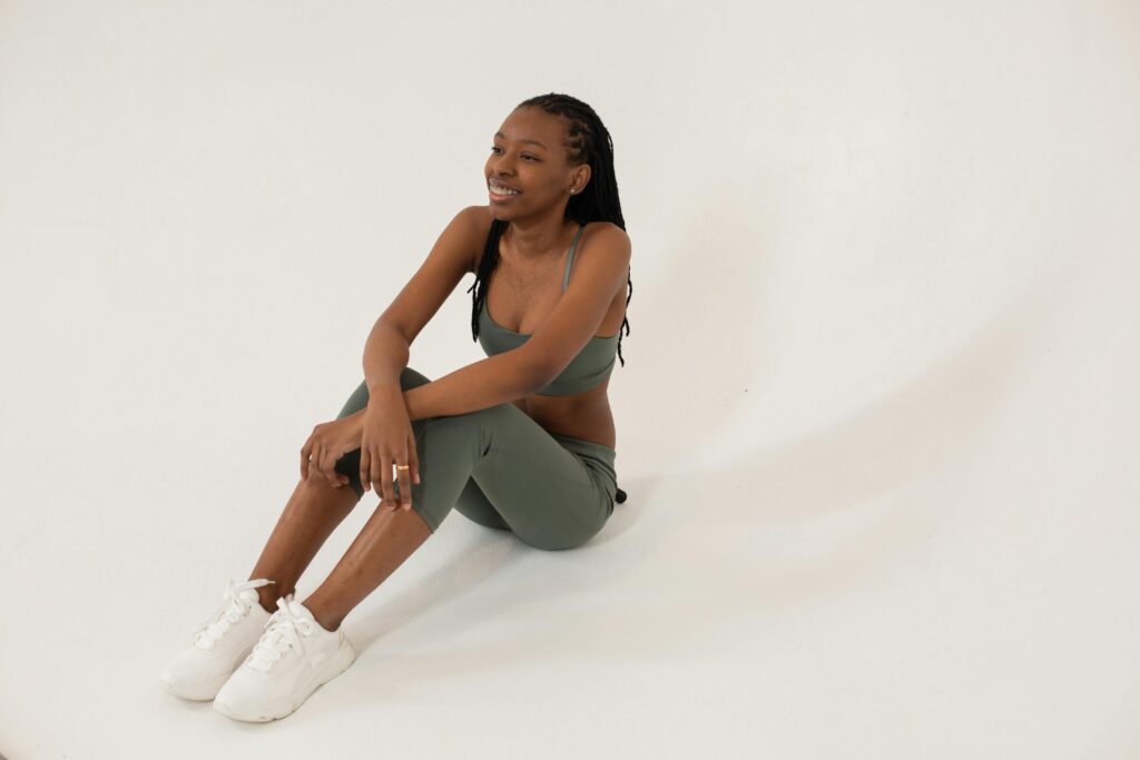 Smiling woman in activewear sitting on the floor after workout