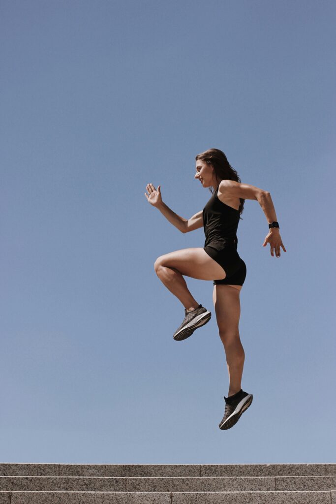 Athletic woman in sportswear jumping outdoors for fitness and strength training