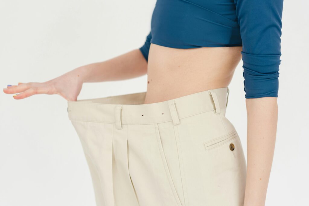 Close-up of woman showing weight loss success by wearing oversized pants